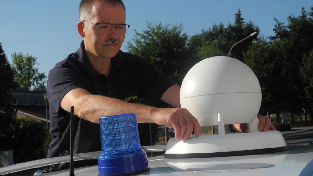 Leiter der Funkwerkstatt bei der Feuerwehr Paderborn montiert Sirene auf Fahrzeugdach.