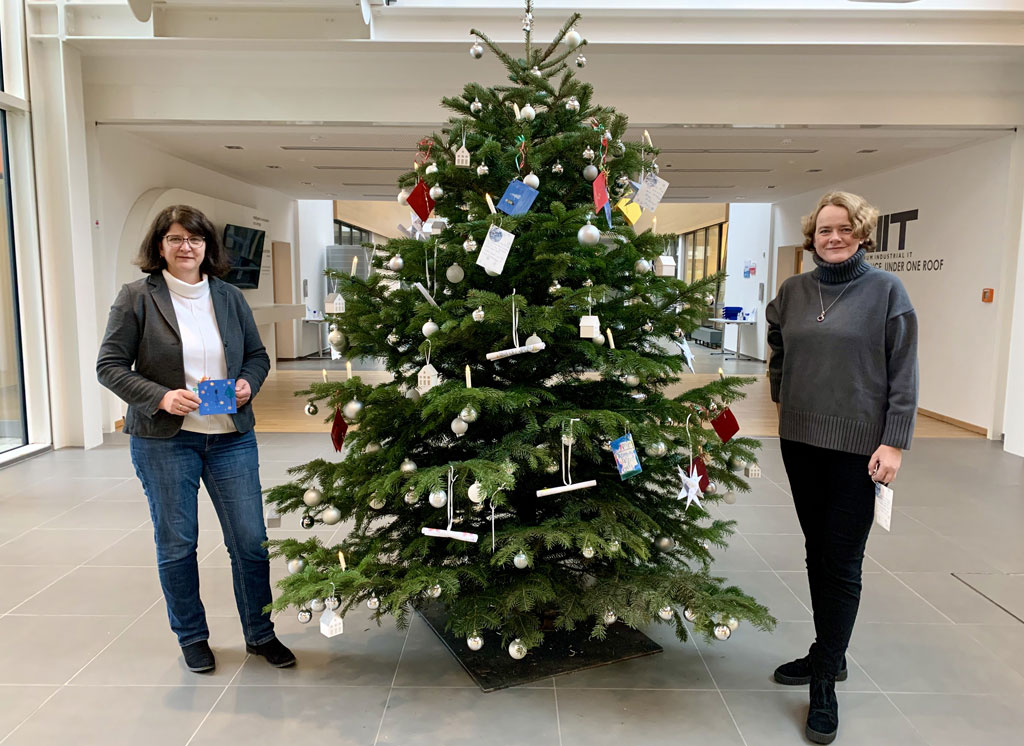 Zwei Frauen, in der Mitte ein Baum.