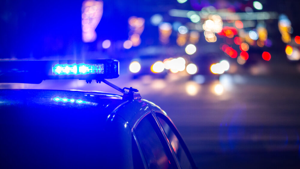 Polizeiauto bei Nacht mit Lichtern der Stadt im Hintergrund
